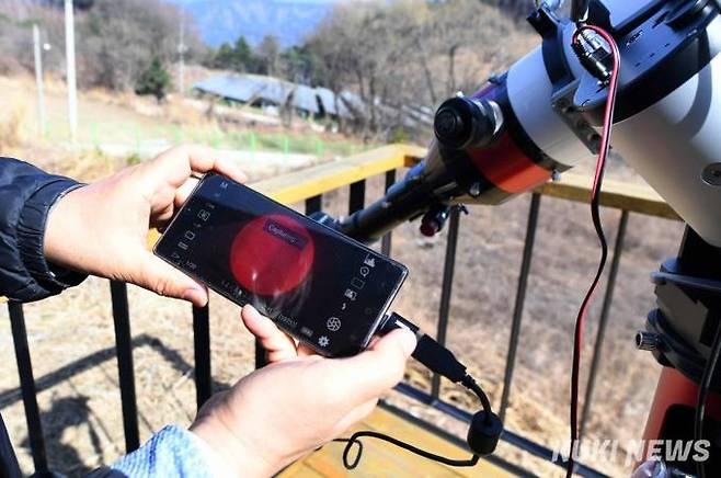 태양망원경에 연결된 스마트폰으로 태양을 선명하게 담아내고 있다.