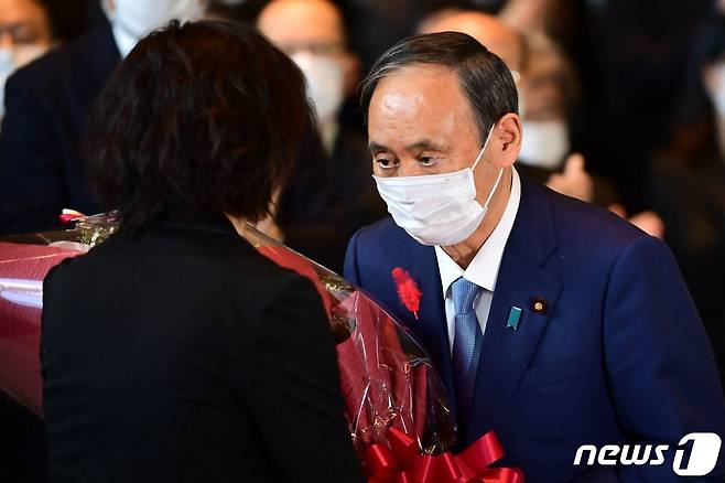 물러나는 스가 요시히데 일본 총리가 4일 (현지시간) 도쿄 총리 관저에서 마지막 각료회의를 마친 뒤 꽃다발을 받고 있다. ⓒ AFP=뉴스1 ⓒ News1 우동명 기자