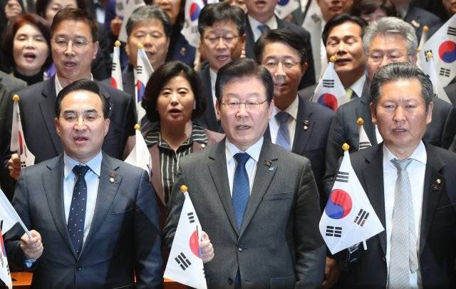 더불어민주당 박홍근 원내대표와 이재명 대표, 정청래 최고위원(왼쪽부터) 등이 16일 국회에서 열린 의원총회에서 윤석열 대통령의 대일 굴욕외교 중단을 촉구하며 태극기를 흔들고 있다. 뉴스1