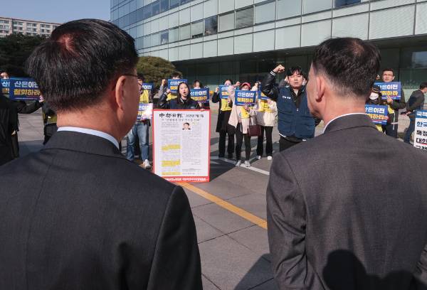 산업은행 노조원들이 27일 오전 여의도 KDB산업은행 본점 앞에서 부산이전 강행 규탄대회를 열고 있다. 노조는 김복규 수석 부행장(뒷모습 왼쪽)과 이근환 부행장(오른쪽)의 출근을 저지했다. 연합뉴스