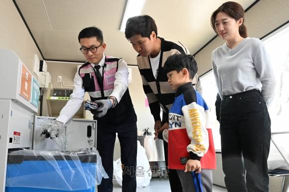 환경보안관이 27일 서울 마포구 구청 광장에 쓰레기를 감량하기 위해 설치한 재활용품 중간 처리장 ‘소각 제로가게’ 1호점에서 시민들에게 캔, 투명페트병 처리기 이용 방법을 설명하고 있다. 홍윤기 기자