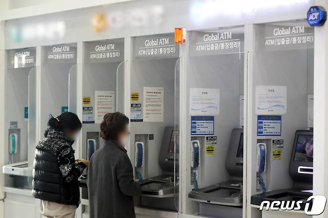 27일 서울 시내 한 건물에 설치된 은행의 현금인출기(ATM)에서 시민들이 입출금을 하는 모습. 2022.12.27/뉴스1 ⓒ News1 황기선 기자
