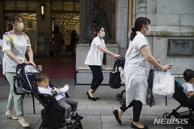 [도쿄=AP/뉴시스]일본 도쿄의 한 백화점 앞을 지나가는 육아여성들. 2023.01.09.