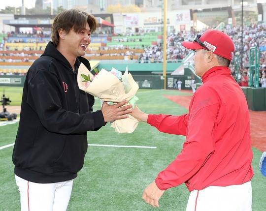 역대 최소경기로 150승을 올린 김광현이 김원형 감독으로부터 축하 꽂다발을 받고 있다.[연합뉴스]