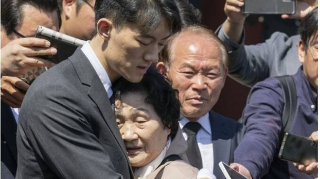 고(故) 전두환 전 대통령의 손자 우원(맨 앞줄 왼쪽)씨가 31일 오전 광주 북구 운정동 국립 5.18 묘지 고 문재학 열사 묘역을 참배한 뒤 문 열사 어머니 김길자 여사(〃 〃 오른쪽)에게 사과하며 포옹하고 있다. 광주=연합뉴스