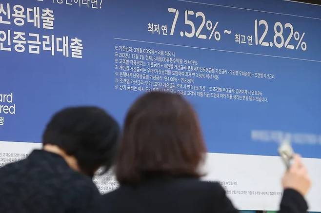 Citizens pass by a banner for a loan product in front of a bank in Seoul on April 2. Yonhap News