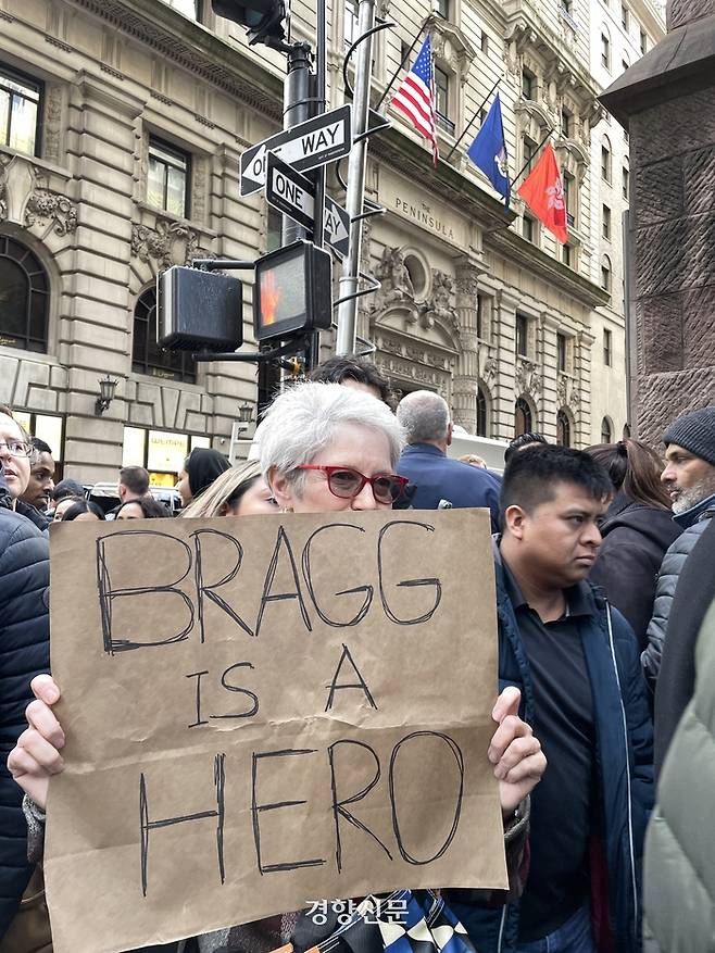 도널드 트럼프 전 미국 대통령이 기소절차를 위해 도착한 3일(현지시간) 뉴욕 맨해튼 트럼프 타워 주변에서 만난 시민이 트럼프 전 대통령을 기소한 앨빈 브래그 맨해튼지방검찰청장을 “영웅”이라고 적은 종이를 들고 있다. 뉴욕/김유진특파원