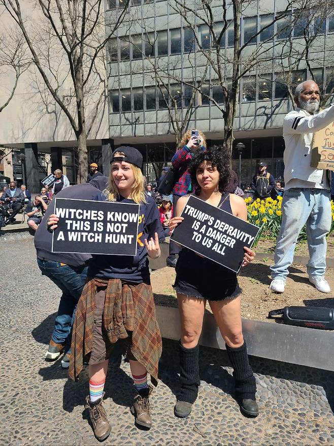 트럼프에 반대하는 20대 여성들이 4일 맨해튼 형사법원 앞 공원에서 "이 기소가 마녀사냥이 아니란 건 마녀도 안다" "트럼프의 나락은 우리 모두에게 위험"이란 피켓을 들고 있다. /뉴욕=정시행 특파원
