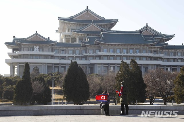 [평양=AP/뉴시스]24일 북한 평양의 인민대학습당 앞에서 마스크를 쓴 두 여성이 북한 인공기를 들고 얘기를 나누고 있다. 2020.12.24.