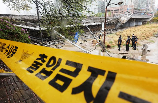 소방관들이 5일 한쪽 보행로가 무너져 내린 경기 성남시 분당구 정자교 주변에서 분주하게 움직이고 있다. 연합뉴스