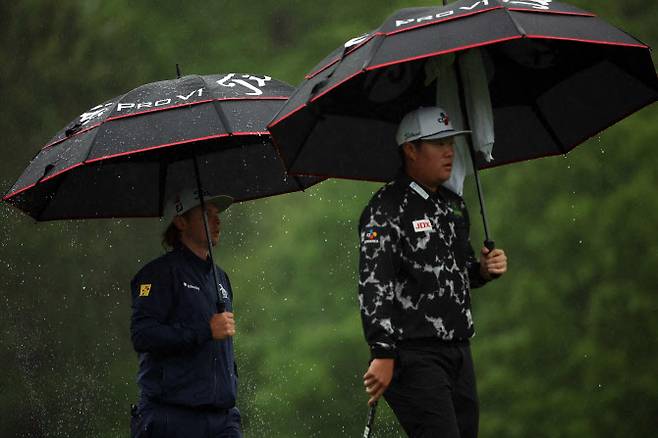 임성재(오른쪽)과 캐머런 스미스가 우산을 쓰고 페어웨이를 걸어가고 있다. (사진=AFPBBNews)