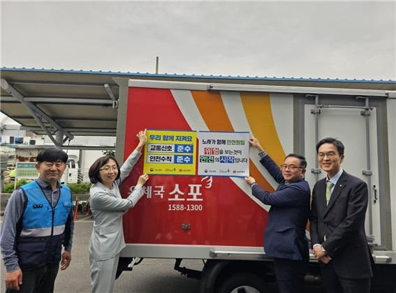 울산우체국 서은숙 국장(왼쪽 둘째부터), 울산고용노동지청 마동준 과장, 안전보건공단 울산지역본부 전상헌 본부장 등이 우체국택배 차량에 안전의식 제고를 위한 시트를 부착하고 있다.