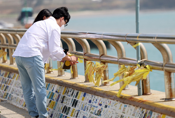 세월호 참사 9주기인 16일 전남 진도군 팽목항 방파제에서 시민들이 노란 리본을 달고 있다. 이날 세월호 출발지인 인천과 목적지였던 제주, 침몰된 세월호가 거치된 목포를 비롯한 전국 곳곳에서 2014년 4월 16일의 참사 희생자를 기억하는 추모 행사가 열렸다. 연합뉴스