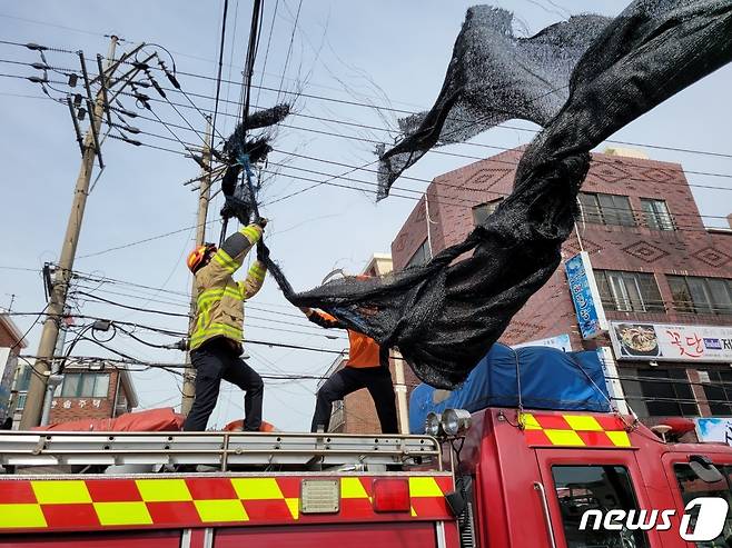 태풍급 강풍이 몰아치고 있는 18일 오전 제주시 연동의 한 도로에서 대형 천막이 전신주에 걸려 안전조치가 이뤄지고 있다.(제주소방서 제공)2023.4.18/뉴스1 ⓒ News1 오미란 기자