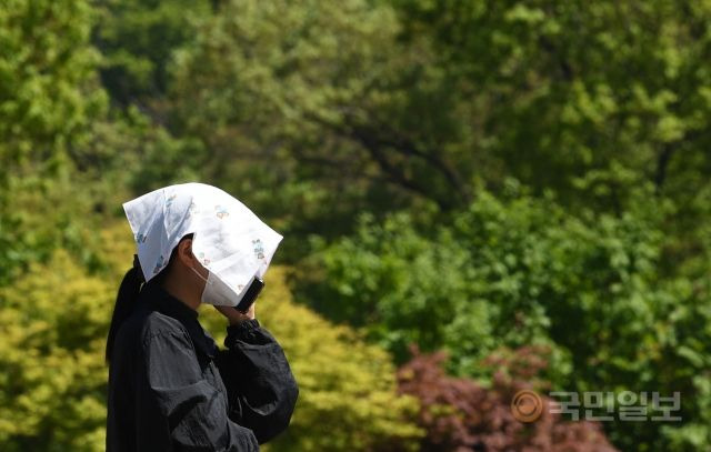 서울의 낮 최고 기온이 28도까지 오르며 초여름 날씨를 보인 19일 서울 남산공원에서 한 시민이 수건으로 햇빛을 가리고 있다.