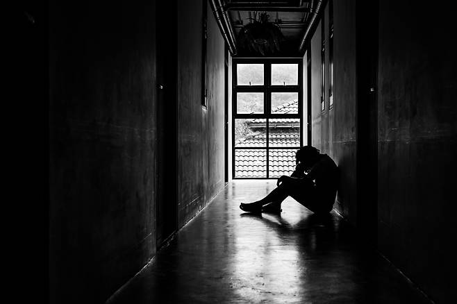 This image shows a young man sitting in the walkway of an unidentified building. (123rf)