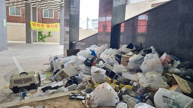 대전 동구 가양동의 한 다가구주택 앞에 쓰레기가 쌓여있다. 그 뒤로는 한 건축사무소의 유치권 행사 플래카드가 걸려있다. /채민석 기자