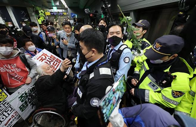 박경석 전국장애인차별철폐연대(전장연) 대표가 21일 오전 서울 지하철 5호선 광화문역에서 탑승 시위 중 지하철 탑승을 저지 당하자 국화꽃을 던지고 있다. / 사진=연합뉴스