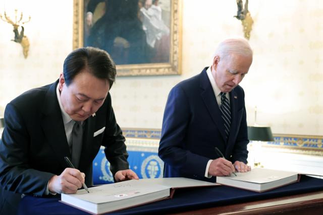 미국을 국빈방문 중인 윤석열 대통령이 25일 워싱턴 백악관에서 조 바이든 미국 대통령과 함께 동맹 70주년 사진집에 서명하고 있다. 대통령실 제공