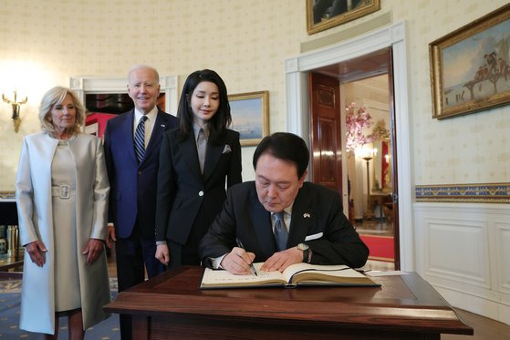 윤석열 대통령이 25일(현지시간) 백악관 관저에서 열린 친교행사에서 김건희 여사와 조 바이든 미국 대통령, 질 바이든 여사가 지켜보는 가운데 방명록을 작성하고 있다. 뉴스1