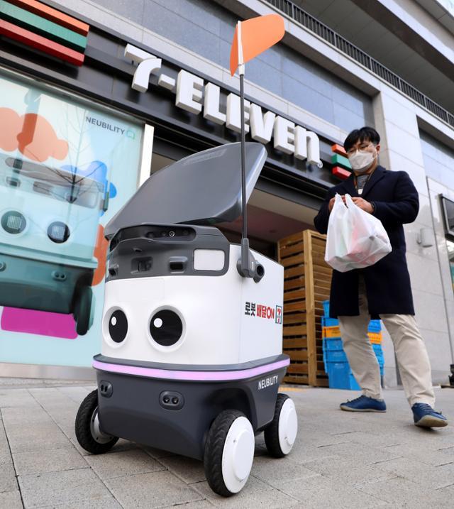 서울 서초구 세븐일레븐 서초아이파크점에서 세븐일레븐이 시범 운영하는 실외 자율주행 배달로봇 '뉴비'를 개발한 뉴빌리티 직원이 배달 시연을 하고 있다. 뉴시스