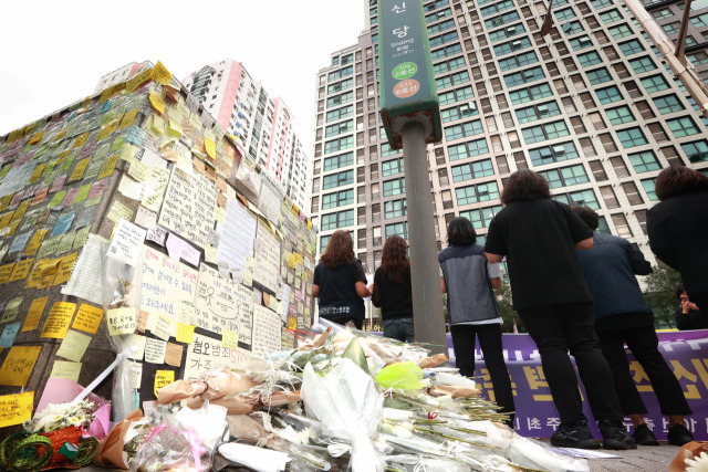 지난해 9월 23일 오전 서울 중구 신당역 10번출구 앞에서 열린 여성 역무원 피살사건에 대한 제도적·인식적 개선책 마련 촉구 기자회견을 하는 참가자들 뒤로 추모의 메시지와 꽃다발이 놓여있다.연합뉴스