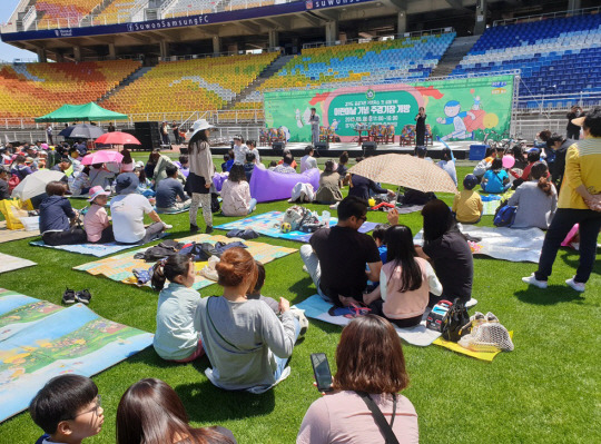 “아이도 어른도 웃음꽃 활짝” 지난 2019년 5월 6일 경기 수원시 우만동 수원월드컵경기장에서 열린 ‘어린이날 기념 주경기장 개방행사’에서 관람객들이 돗자리에 앉아 여가를 즐기고 있다. 경기도수원월드컵경기장관리재단 제공