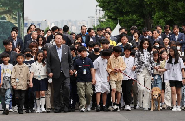 윤석열 대통령과 김건희 여사가 4일 서울 용산 대통령실의 앞마당에 조성된 용산어린이정원 개방 행사에서 어린이들과 손을 잡고 입장하고 있다. 연합뉴스(대통령실통신사진기자단)