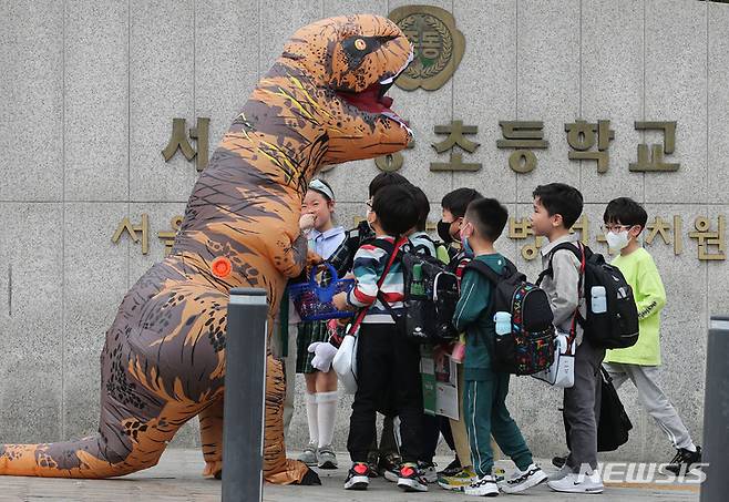 [서울=뉴시스] 권창회 기자 = 어린이날을 하루 앞둔 4일 오후 서울 마포구 한 초등학교 앞에서 공룡분장을 한 시민이 어린이들에게 사탕을 나눠주고 있다. 2023.05.04. kch0523@newsis.com