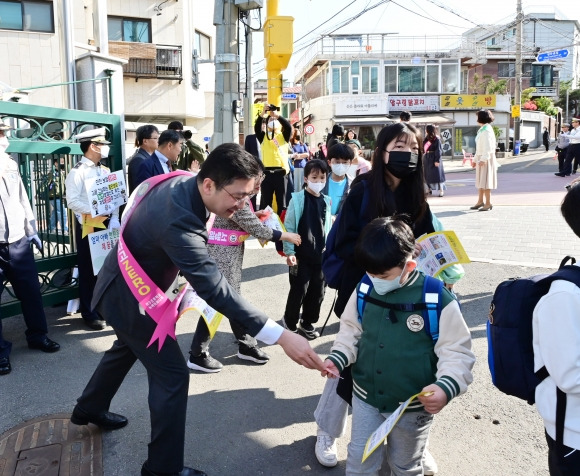 고광민 의원이 이수초등학교에서 진행된 교통안전 캠페인에 참여해 어린이들에게 보행안전 원칙이 기재된 안내문을 나눠주고 있다.