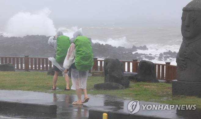 (서귀포=연합뉴스) 박지호 기자 = 제주에 호우특보가 내려진 4일 제주 서귀포시 사계해안도로에서 우비로 무장한 배낭여행객이 걷고 있다.