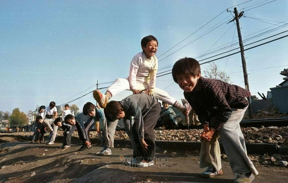 컬러로 되살아난 그때 ‘웃음’처럼… ‘어린이 해방’ 100년, 신나게 놀자 - ‘어린이를 윤리적 압박으로부터 해방하야 … 완전한 인격적 예우를 허하라.(중략) 그들이 고요히 배우고 즐거이 놀기에 족할 각양의 가정 또는 사회적 시설을 행하게 하라.’ 100년 전 방정환이 결성한 소년운동협회가 발표한 ‘어린이해방선언’입니다. 1979년 서울의 한 기찻길 옆에서 등넘기를 하며 해맑게 웃는 아이들을 찍은 서울신문의 흑백사진을 컬러로 복원해 보니 아이들의 발그레한 얼굴이 더욱 생기 있어 보입니다. 그 시절 이토록 즐거웠던 우리가 어른이 된 지금 아이들에게 이런 ‘고요하고 즐거이’ 지낼 환경을 만들어 주고 있을까요. 아이들 웃음은커녕 탄생의 울음조차 사라지는 현실을 고민해야 하는 시대, 5일 제101회 어린이날을 맞아 아이들의 웃음소리가 가득한 날이 끊이지 않고 계속되기를 기대해 봅니다. 서울신문 멀티미디어부