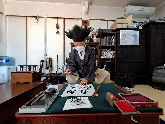 Calligrapher Jung Chun-hwa writes a four-character saying for a visitor on April 20 in Hadong, South Gyeongsang Province (Lee Si-jin/The Korea Herald)