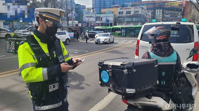 23일 오후 2시9분 서울 관악구 신림동 구로디지털단지역 사거리 인근. 이륜차 합동단속에 나선 서울 관악경찰서 소속 경찰관이 신호·지시 위반을 한 오토바이 운전자에게 범칙금을 부과하고 있는 모습./사진=김도균 기자