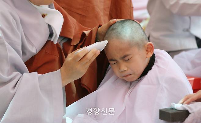 한 동자승이 삭발을 하는 동안 눈을 질끈 감고 있다.