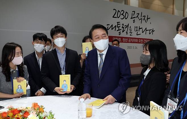 MZ세대 공무원과 대화하는 윤석열 대통령 (세종=연합뉴스) 서명곤 기자 = 윤석열 대통령이 지난해 5월 26일 오전 세종시 정부세종청사에서 열린 세종청사 MZ세대 공무원 간담회에서 '90년생 공무원이 왔다'라는 책자를 들고 참석자들과 대화하고 있다.     2022.5.26 seephoto@yna.co.kr