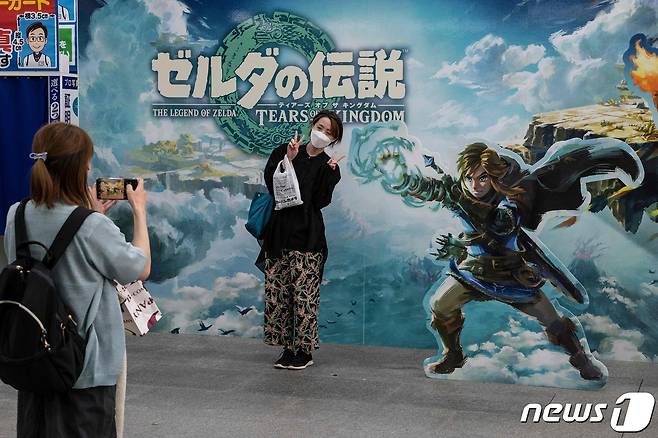 12일 일본 도쿄에서 인기 게임 '젤다의 전설' 신작을 구입한 여성이 광고벽 앞에서 기념 사진을 찍고 있다. ⓒ AFP=뉴스1 ⓒ News1 권진영 기자