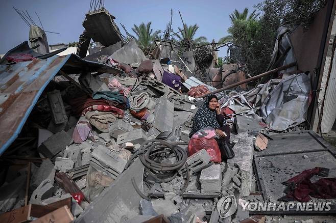 이스라엘군의 공습으로 무너진 가자지구의 건물에 한 여성이 앉아 있다. [AFP 연합뉴스 자료사진. 재판매 및 DB 금지]