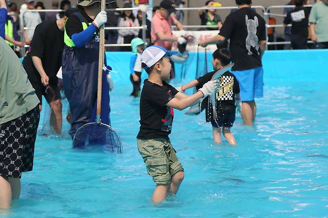 충남 서천 마량진항에서 열리고 있는 광어·도미 축제에서 한 어린이가 맨손으로 광어를 잡고 즐거워 하고 있다. 서천군 제공