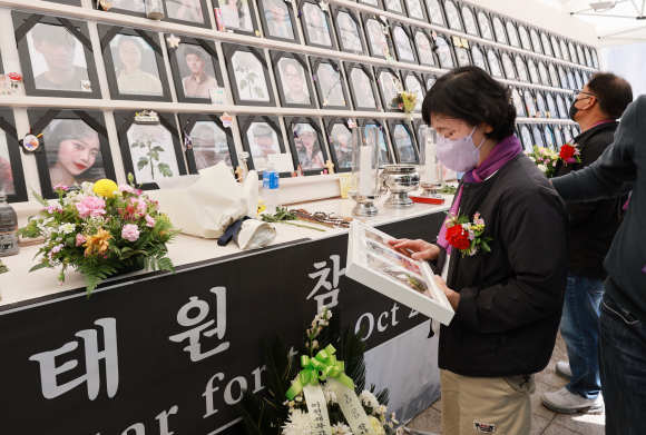 아이를 바라보며 - 8일 서울 중구 서울광장 이태원 참사 희생자 합동분향소 앞에서 열린 ‘10.29 이태원 참사 200일, 200시간 집중추모행동 주간’ 선포 기자회견에서 한 참사 유가족이 촛불갤러리 작가들이 희생자들과 가족들의 사진을 소재로 그린 ‘기억 그림’을 분향소 영정 앞에서 바라보고 있다. 2023.5.8 연합뉴스