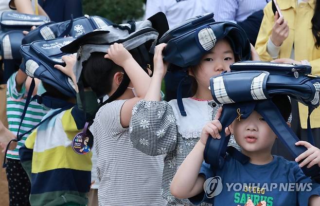 가방은 머리 위로, 어른보다 더 열심히 (서울=연합뉴스) 홍해인 기자 = 16일 오후 정부서울청사에서 열린 414차 민방위의 날, 민방공 대피 훈련에서 청사 푸르미 어린이집 원아들이 머리를 가방으로 가린 채 안전교육 장소로 이동하며 훈련에 참여하고 있다. 2023.5.16 hihong@yna.co.kr