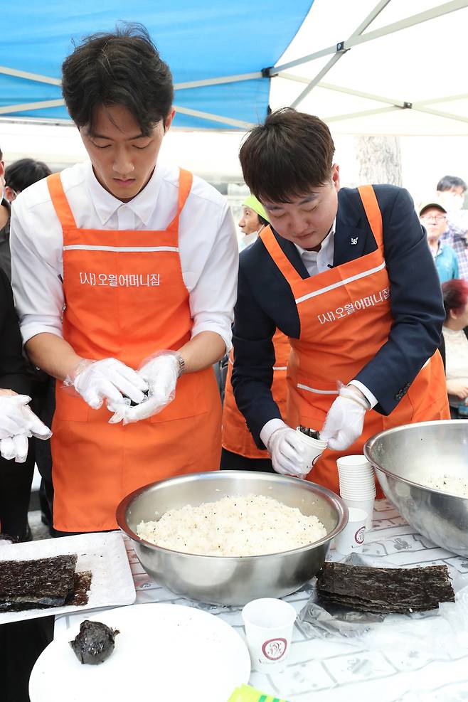 전직 대통령 고 전두환씨의 손자 전우원씨가 17일 광주 동구 금남로에서 열린 5·18 시민 난장 오월 주먹밥 체험 부스에서 국민의힘 이준석 전 대표와 주먹밥을 만들고 있다.  / 사진=연합뉴스