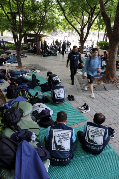 17일 오전 서울시민들이 전날 총파업 결의대회 후 청계광장 인근에 앉아있는 민주노총 건설노조원들을 지나가고 있다. 연합뉴스