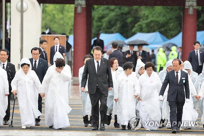 오월어머니회와 함께 입장하는 윤석열 대통령 (광주=연합뉴스) 진성철 기자 = 윤석열 대통령이 18일 광주 북구 국립5·18민주묘지에서 열린 제43주년 5·18민주화운동 기념식에 오월어머니회 회원들과 함께 입장하고 있다. 2023.5.18 zjin@yna.co.kr