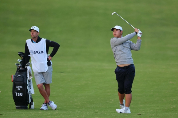 19일 PGA 챔피언십 1라운드 6번홀에서 온 몸이 진흙밭에 빠지는 곤욕을 겪은 김주형이  개울에 씻은 바지를 걷어올린 채로 어프로치샷을 하고 있다. [AFP 연합뉴스]