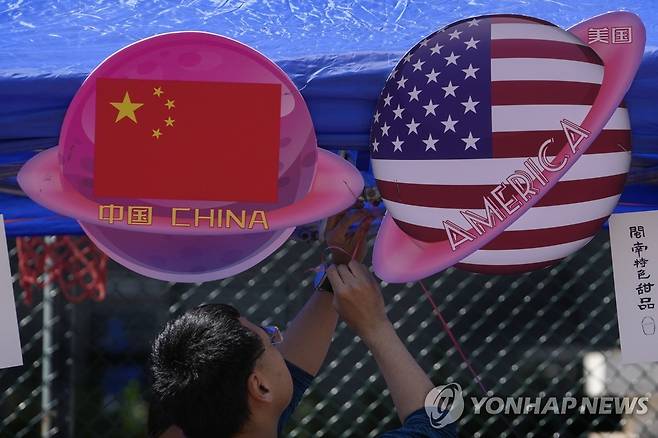 베이징 상점에 걸린 중국·미국 국기 상징물 지난 13일 중국 베이징의 한 식료품상이 중국과 미국 국기 모양을 한 위성 모형을 거는 모습. [AP=연합뉴스 자료사진. 재판매 및 DB 금지]