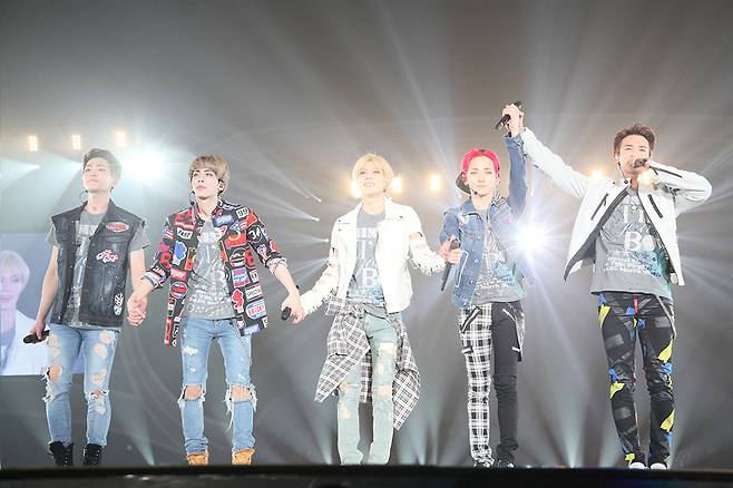 SHINee members, (from left) Onew, Jonghyun, Taemin, Key and Minho, hold hands on stage during the band's 2015 Tokyo Dome debut concert. (SM Entertainment)