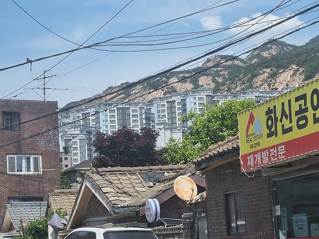 25일 서울 은평구 불광동 불광5구역 모습. 사진 아래쪽 중간 지층집에 자리잡은 점집과 '재개발 전문'을 내건 공인중개업소 뒤로 불광3구역 재개발 아파트인 '북한산 힐스테이트3차'가 보인다. /백윤미 기자