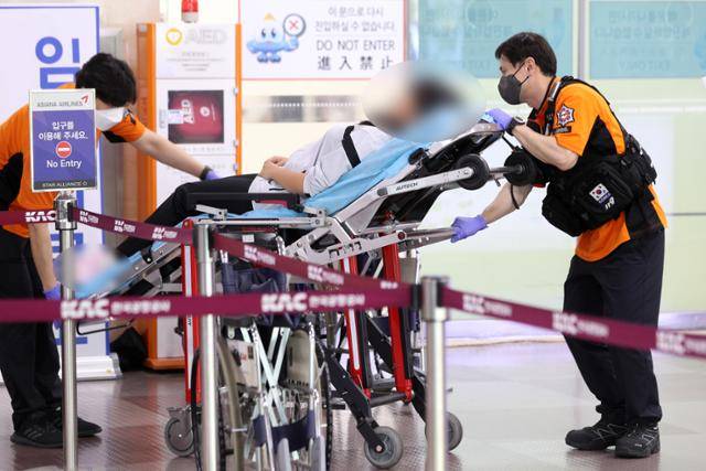26일 오후 착륙 도중 출입문이 열린 아시아나 항공기 승객 중 호흡곤란을 호소한 사람이 119에 의해 긴급 이송되고 있다. 대구=연합뉴스