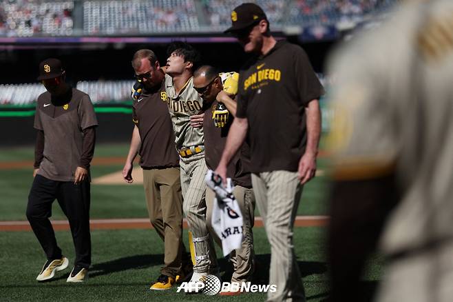 김하성(왼쪽에서 세 번째)이 26일(한국시간) 워싱턴 내셔널스와 원정 경기에서 2회 자신의 파울 타구에 무릎을 강타당한 뒤 트레이너 2명의 부축을 받으며 그라운드를 빠져나가고 있다. /AFPBBNews=뉴스1
